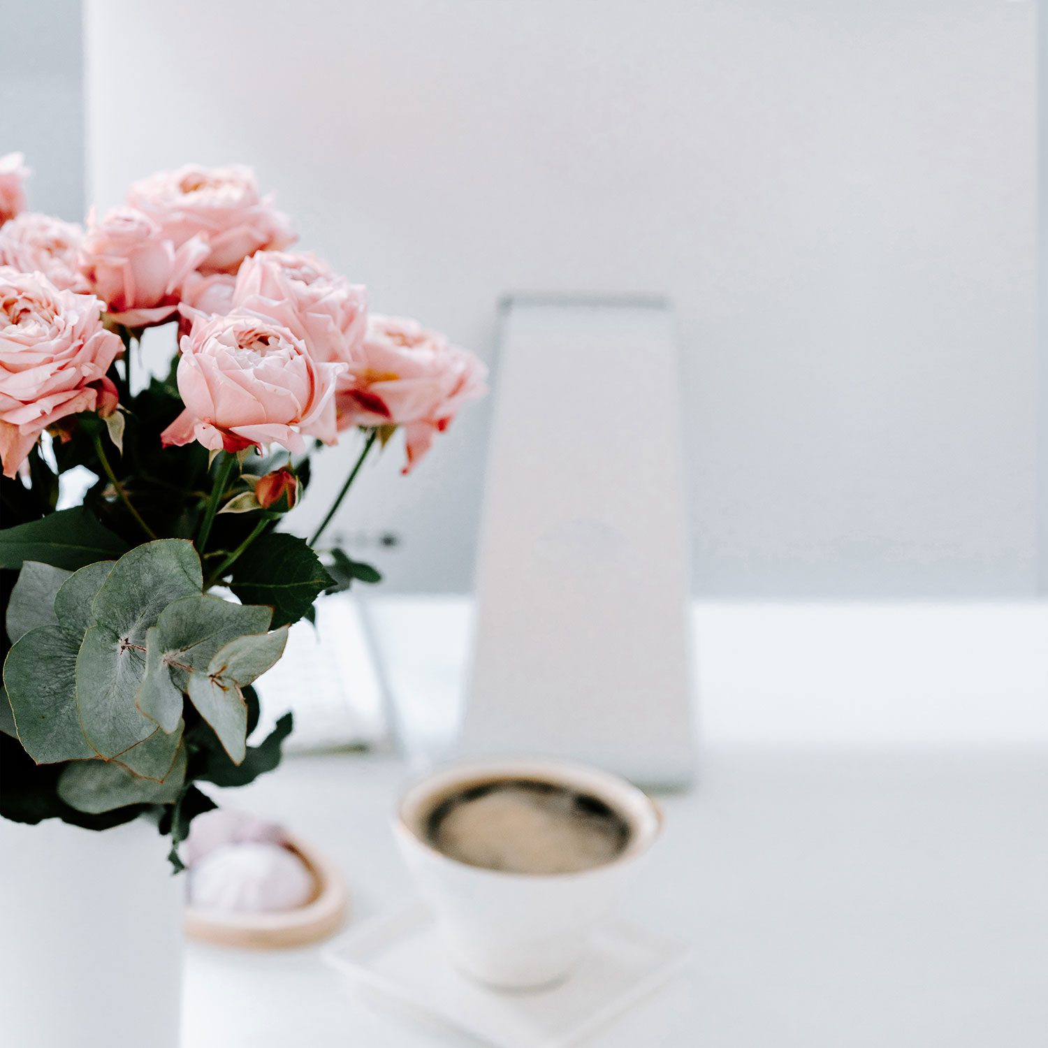 computer with cup of tea and bouquet of roses in front